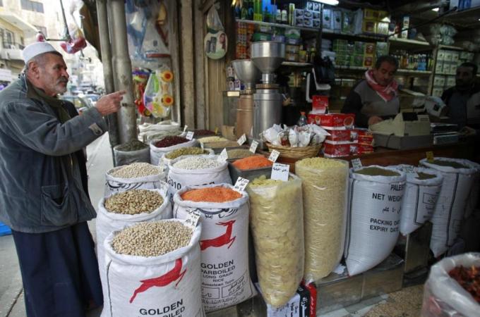 A customer speaks to a shop vendor at a market in Amman
