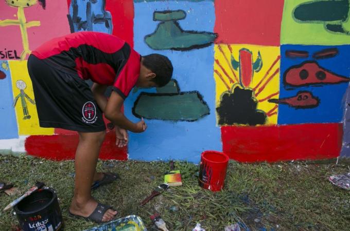 A youth paints in the walls of what used to be the Panamanian military headquarters, one day before the 25th anniversary of the US invasion, in what's now a park in El Chorrillo community of Panama City [AP]