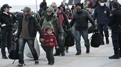 Immigrants walk with their belongings after disembarking from a crippled freighter [AP]