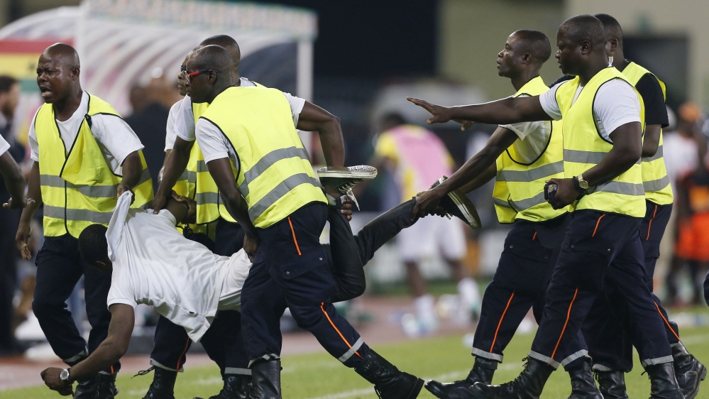 Security detain an Equitorial Guinea fan on the pitch after he tried to attack the referee during the African Cup semi-final match against Ghana in Malabo