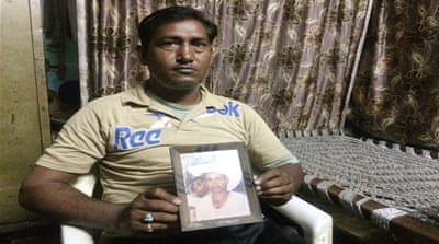 Mohammed Qadir holds up a photo of his father whose body was never found [Sonia Paul/Al Jazeera] 