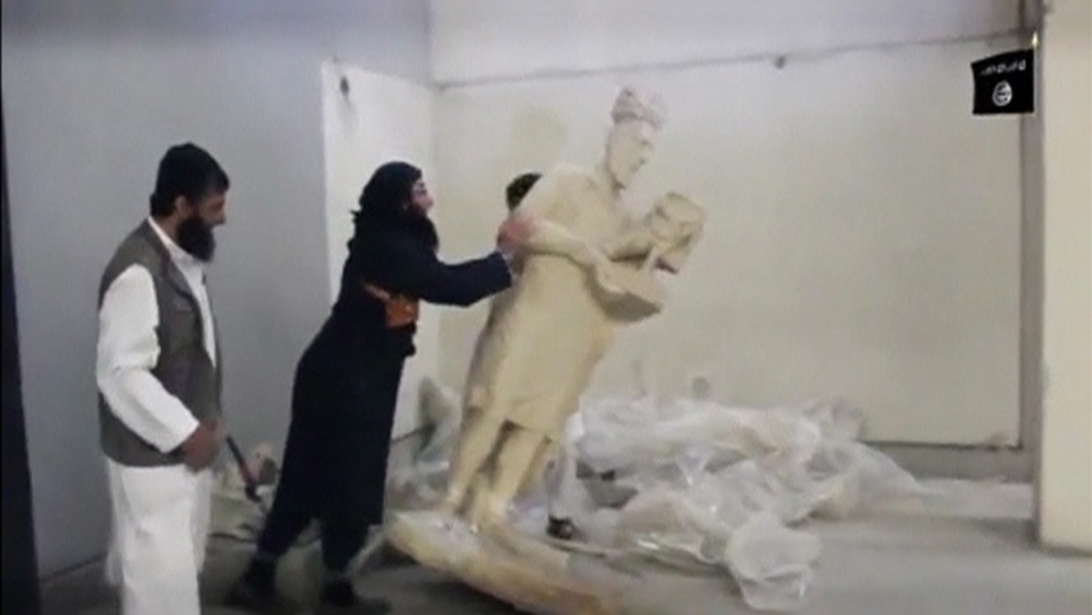 A man topples a statue in a museum at a location said to be Mosul