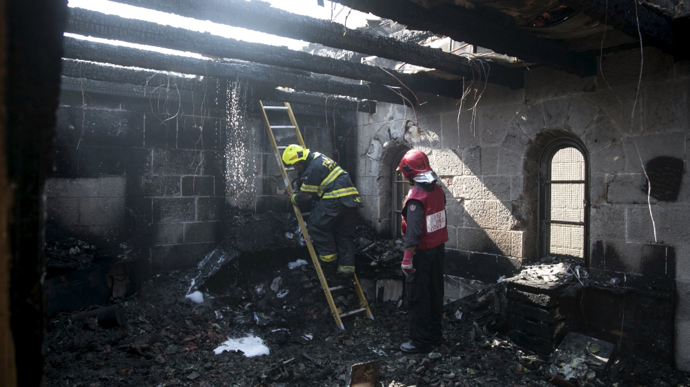 An Israeli fire fighter climbs a ladder in the Church of Loaves and Fishes in northern Israel