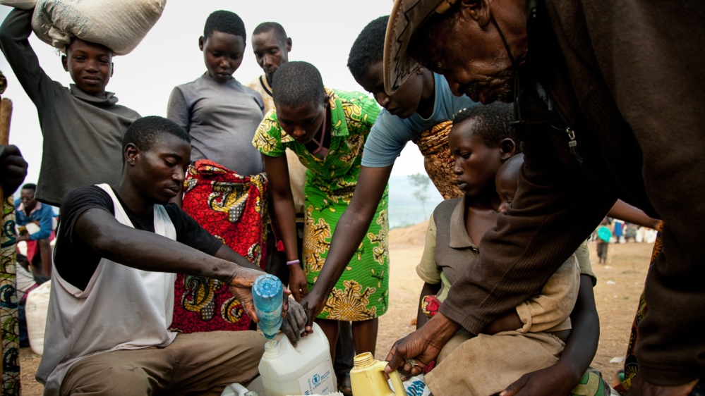 A group of inhabitants of the Mahama refugee camp divide up their monthly food ration between different families. [Zoe Flood/Al Jazeera]