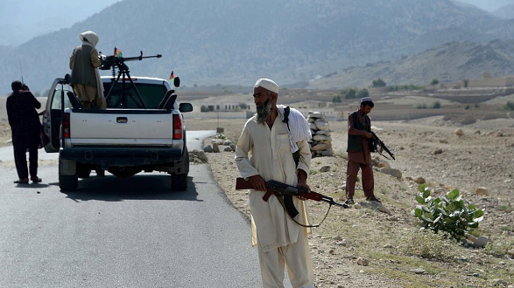 Afghan Local Police keep watch along the road near a checkpoint, set alight by ISIL fighters during overnight clashes between Afghan forces and ISIL groups, in Nangarhar province [Getty]