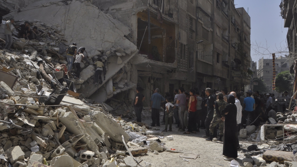 Residents inspect a site hit by what ac Yarmouk