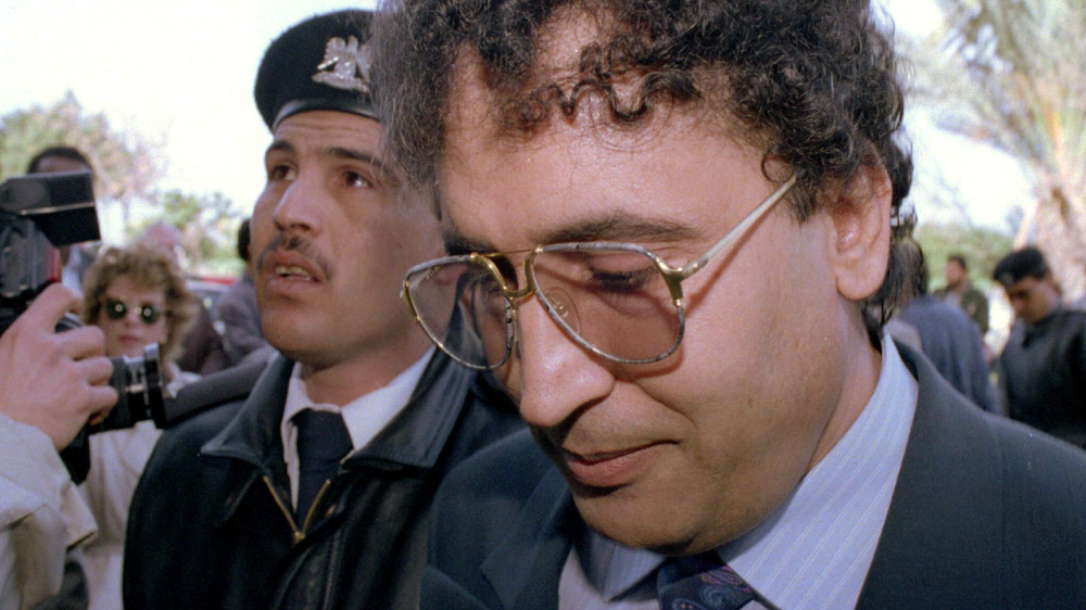 Abdel Basset al-Megrahi, right, is escorted by a police officer to court in Tripoli, Libya, February 18, 1992