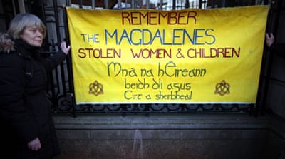 A woman holds a poster in solidarity with Justice for Magdalene Survivors in Dublin, Ireland, in 2013, prior to Prime Minister Enda Kenny's apology on behalf of the Irish people for ignoring the conditions at the laundries between 1922 and 1996. [Peter Morrison/AP]