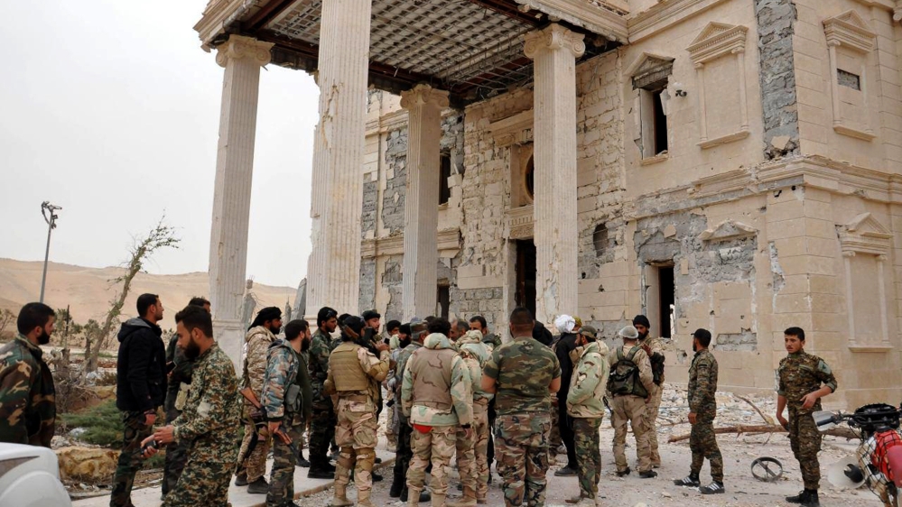 Syrian government soldiers gather outside a damaged palace, in Palmyra
