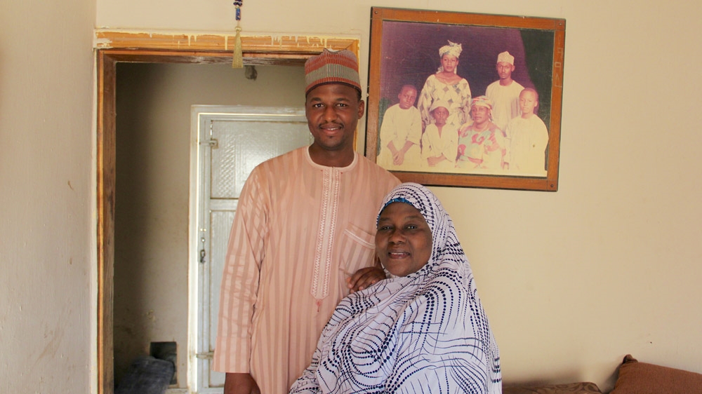 Balaraba Ramat Yakubu with her third child, Muhammed. A picture of her with all five of her children hangs on the wall [Femke van Zeijl/Al Jazeera]