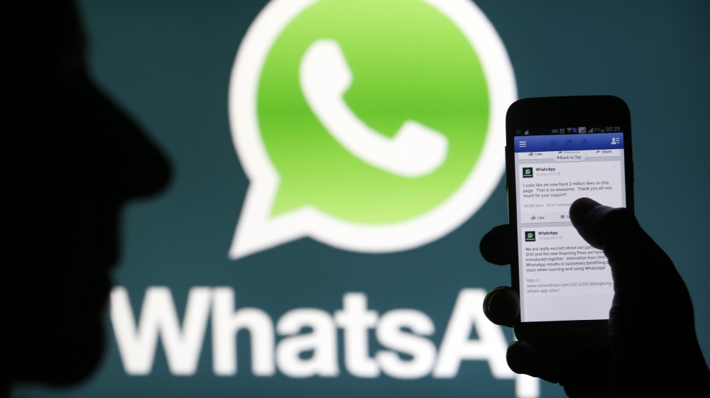 A Whatsapp App logo is seen behind a Samsung Galaxy S4 phone that is logged on to Facebook in the central Bosnian town of Zenica