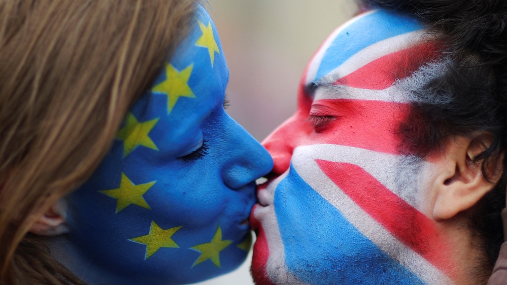 Two activists with the EU flag and Union Jack painted on their faces kiss each other in front of Brandenburg Gate to protest against Brexit in Berlin
