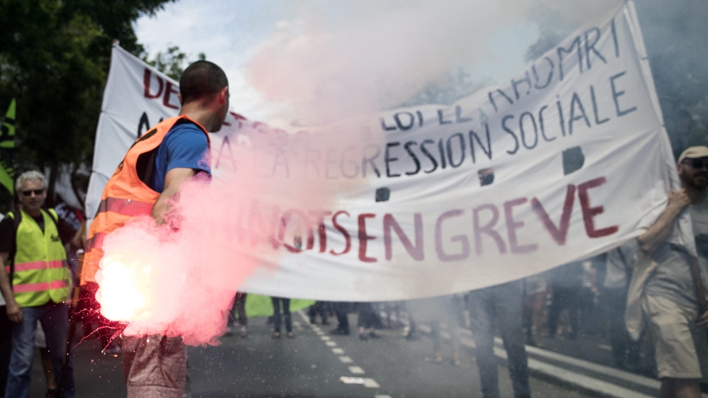 A protester holds a flare in front of a banner reading ''Railroad workers on strike'' during a national demonstration against the Labour Law reform in Paris, France [EPA]