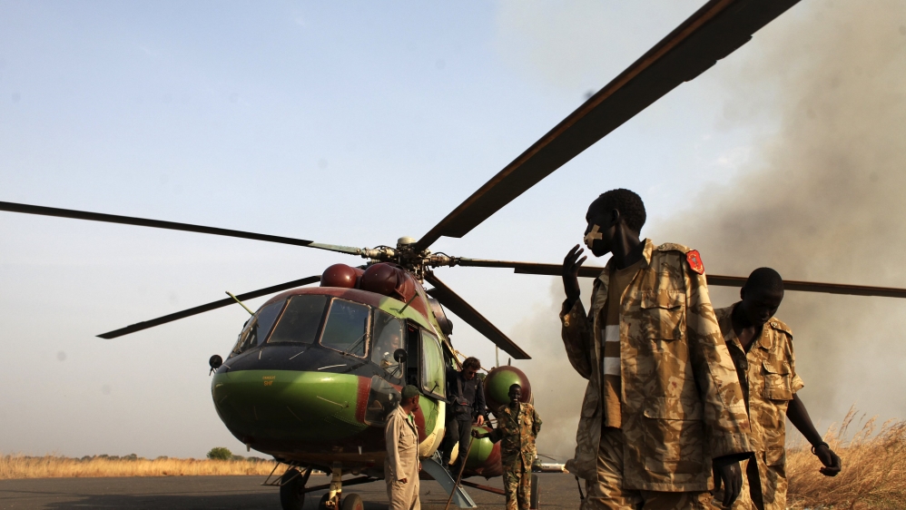 SPLA soldiers and a journalist leave a helicopter after a flight to Bor, in Juba