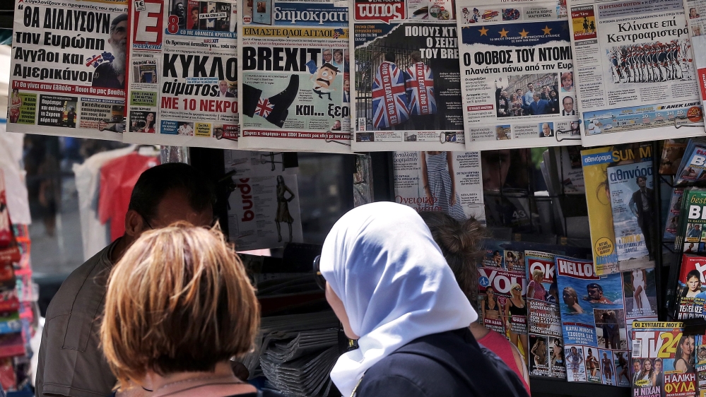 People glance at the frontpages of Greek newspapers hanging on a kiosk in central Athens, Greece [EPA]