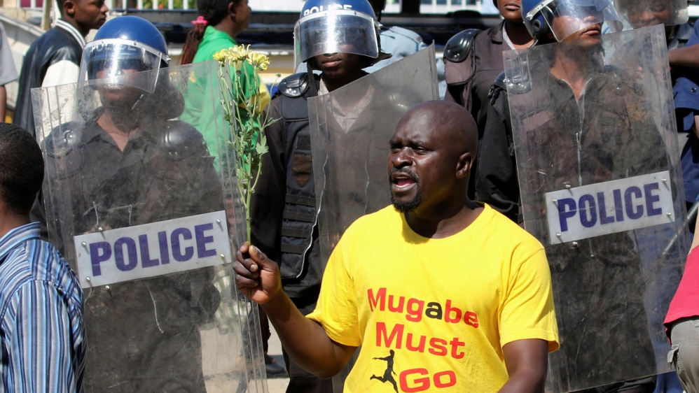 Zimbabwe''s anti-riot policemen look on as a protester holds flowers during a demonstration against central bank plans to re-introduce local banknotes in Zimbabwe''s capital Harare