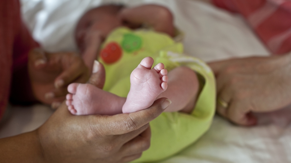 A couple whose baby was born using a surrogate pose for a photo in Anand, India