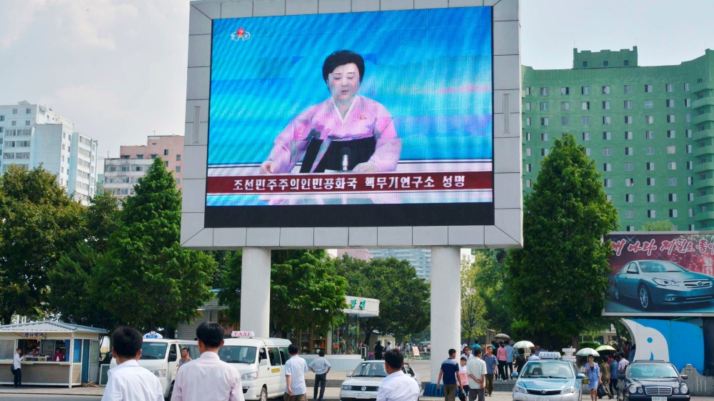 North Koreans walk past near a huge screen broadcasting the government''s announcement on North Korea''s fifth nuclear test in Pyongyang