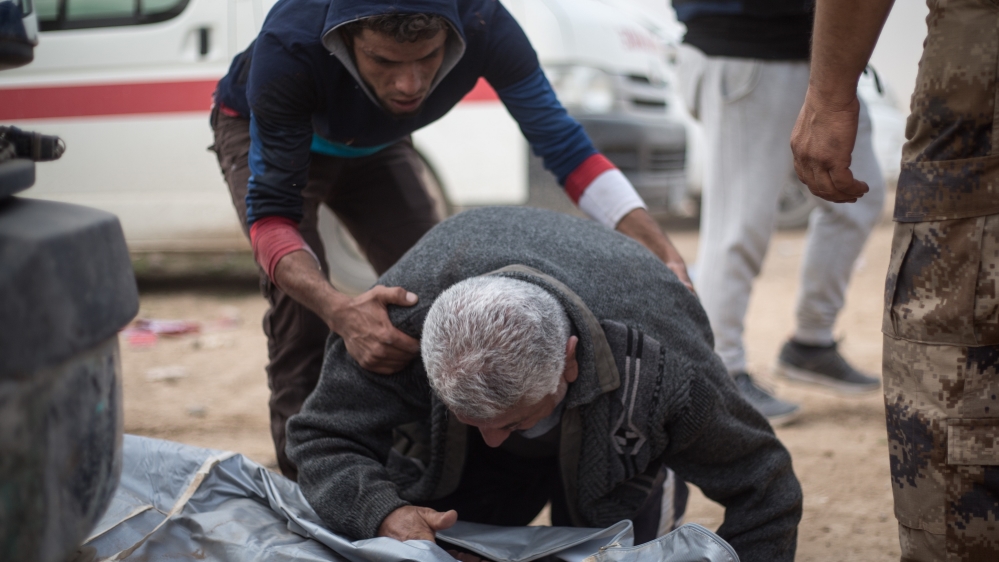 The father of Maytham, 15, opens the body bag containing his son at an outdoor clinic in Mosul's Samah district. Maytham was killed by a mortar attack minutes earlier [John Beck/Al Jazeera]