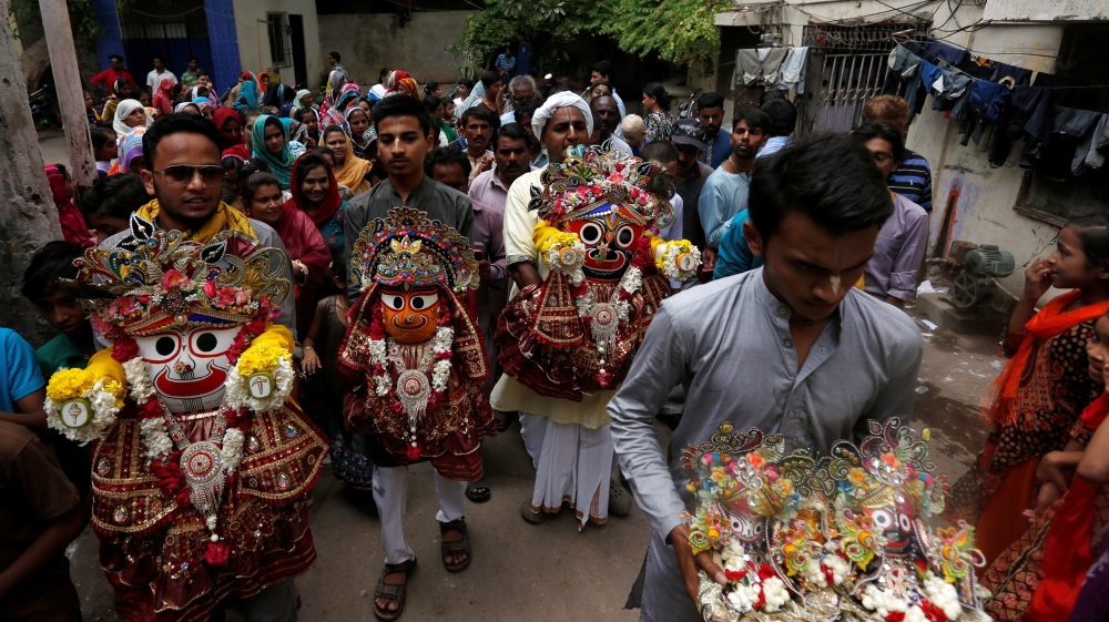 Hindu devotees hold the deities of lord Jagannath along with others during the Rath Yatra, or chariot procession in Karachi