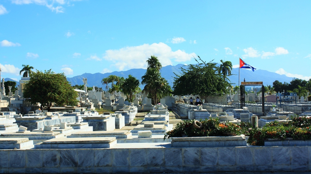 The only things that separate the cemetery from the poor neighbourhood of Aguero behind it are a wall and a dusty embankment [Al Jazeera] 