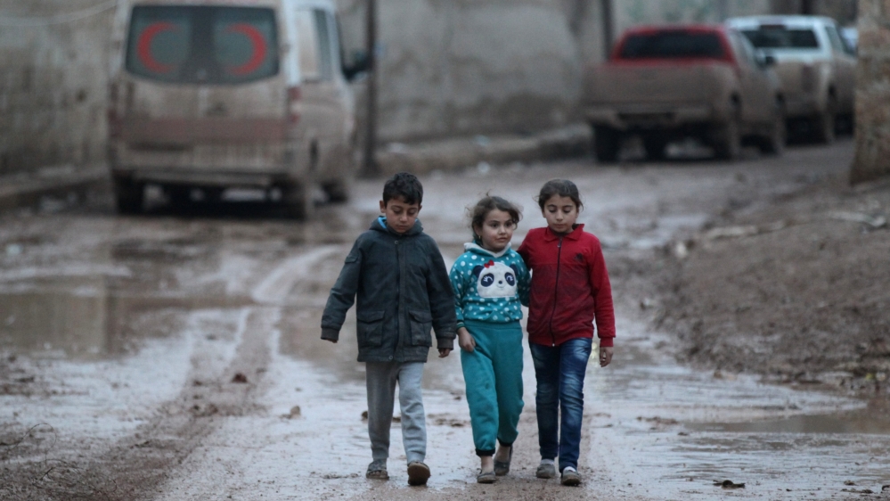 Children walk near a parked ambulance vehicle in al-Rai town, Aleppo
