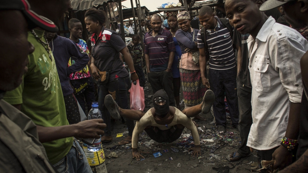 Vini, a street artist, performs in the market of the Lubugi district of Kinshasa [Francesca Volpi/Al Jazeera]