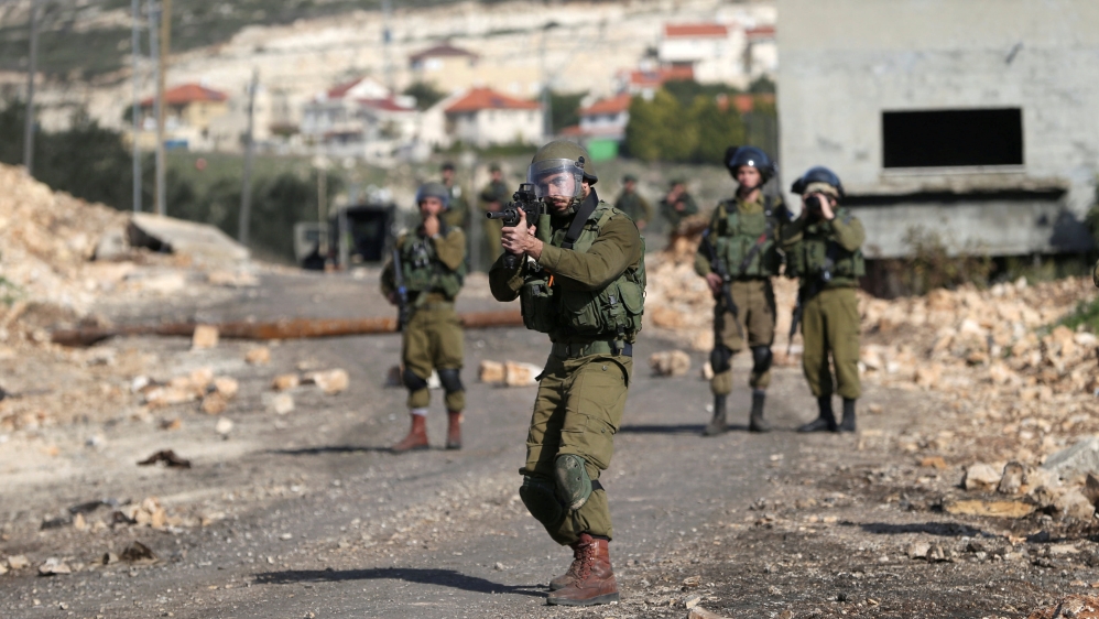 Israeli soldier aims his weapon towards Palestinian protesters during clashes following a protest against the near-by Jewish settlement of Qadomem, in the West Bank village of Kofr Qadom near Nablus