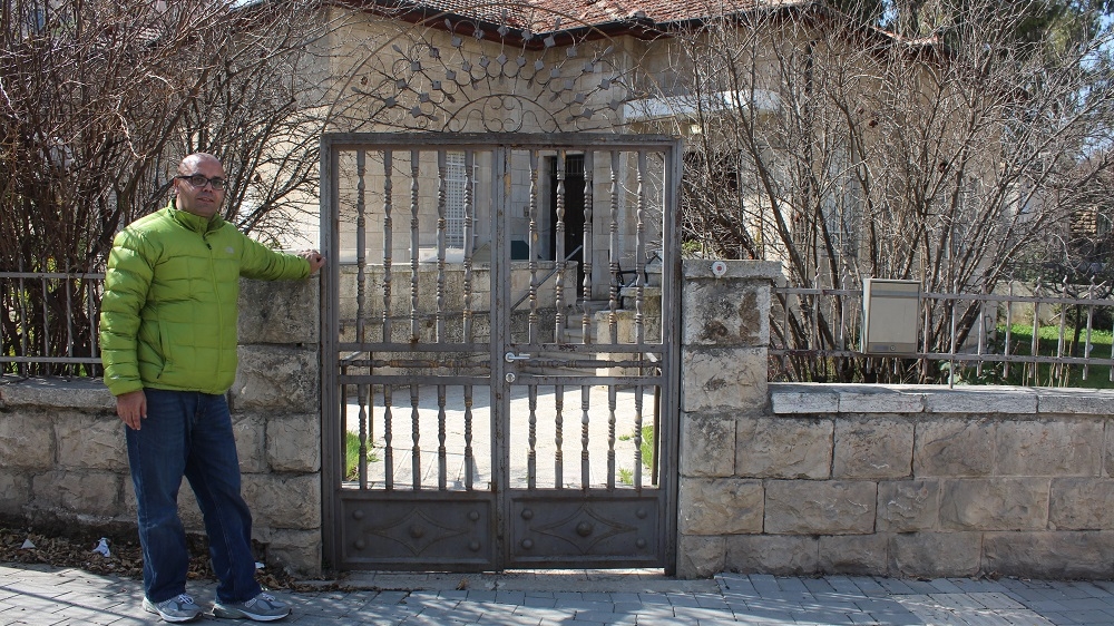 Anwar stands in front of his mother's home in Baka, which she was forced to leave in 1948. The house is now occupied by Jewish Americans [Mary Pelletier/Al Jazeera]