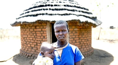 Beatrice Eimani and her son outside their hut in Egge, the village bordering the Adjumani settlement [Yilmaz Polat/Al Jazeera]