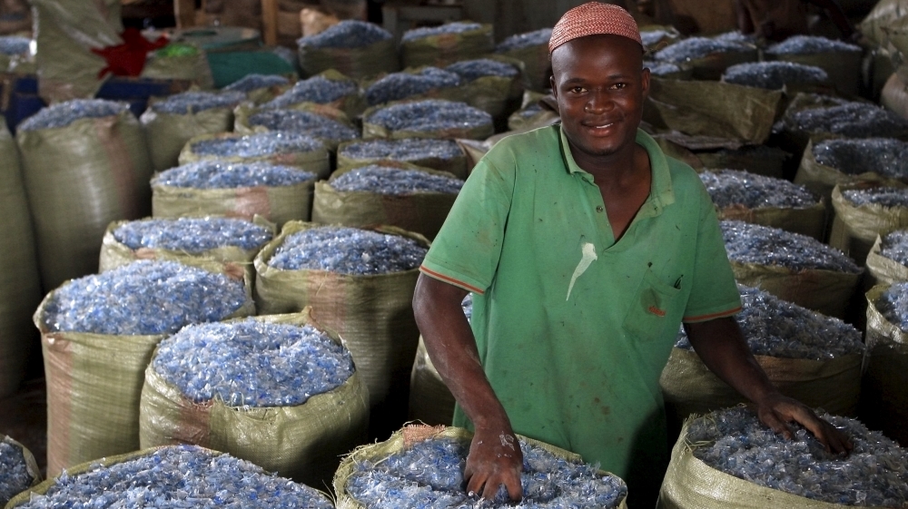 An employee of a recycling plant fills up sacks with plastics pellets ready for export to China at their factory at a dumping site on the outskirts of Kampala