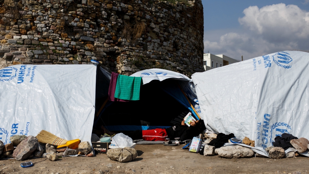 A migrant reads a book outside his tent at the Souda municipality-run camp for refugees and migrants on the island of Chios