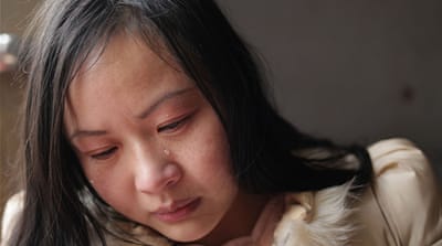 Lin Chunhong cries as she talks about how others often made her feel inferior when she was a child because she was adopted [Han Meng/Al Jazeera]