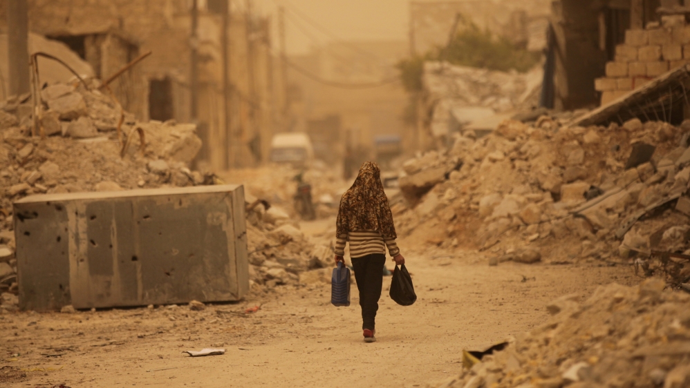 A civilian walks along a street during a dust storm in the northern Syrian town of al-Bab, March 10, 2017 [Khalil Ashawi/Reuters]