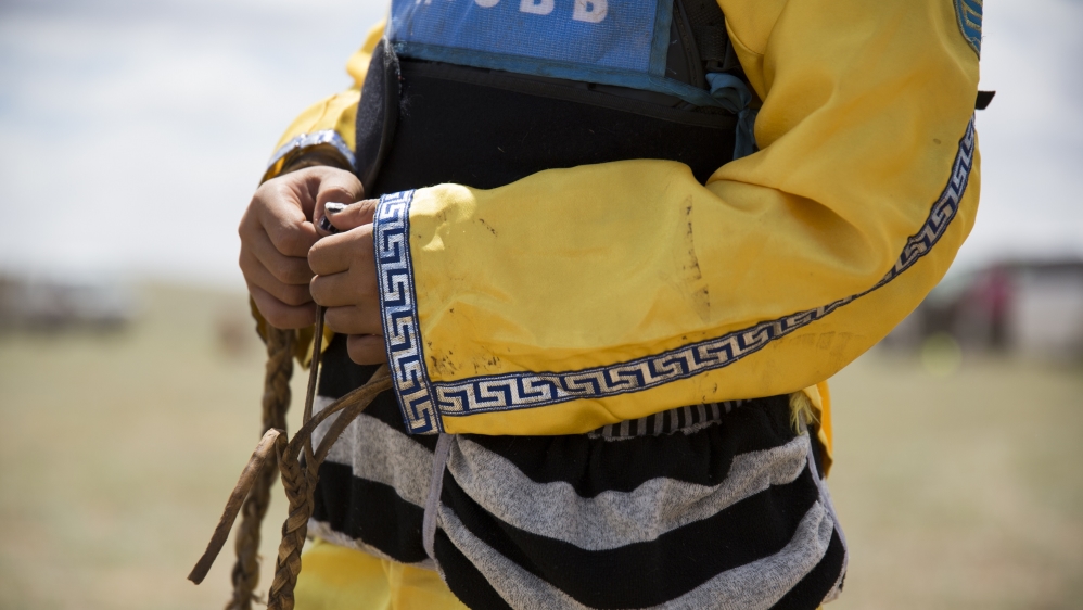 Bujinlkham Damdinsuren holds her whip at the finish line at the end of the 24km race. She was disappointed with her 23rd place finish but will take part again next year [Hannah Griffin/Al Jazeera]