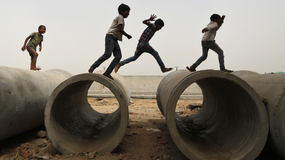 Children play on cement sewer pipes near a construction site in Ahmedabad