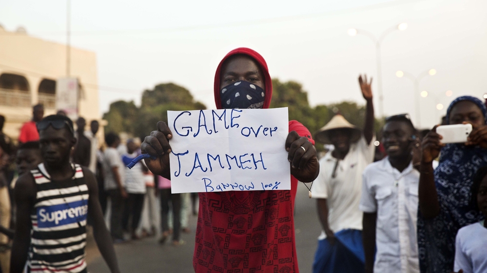 A man holds a banner as Gambians cheer in Serrekunda, Gambia, January 19, 2017, after watching Adama Barrow be sworn in as Gambian president on a television broadcast from the Gambian Embassy in Dakar, Senegal