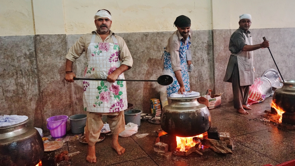 Muslim cooks Muhammad Rafique and Muhammad Mushtaq stir large pots of food served in langars in Nankana Sahib [Sabrina Toppa/Al Jazeera]