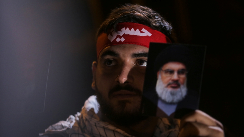 A Lebanon''s Hezbollah supporter holds a photograph of leader Sayyed Hassan Nasrallah during his address via a video screen during a ceremony of the latest day of Ashoura in Beirut