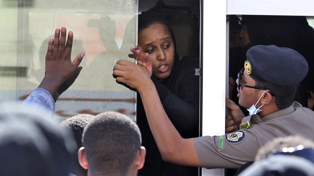 An Ethiopian worker speaks with a Saudi security force while waiting to be repatriated, in Manfouha