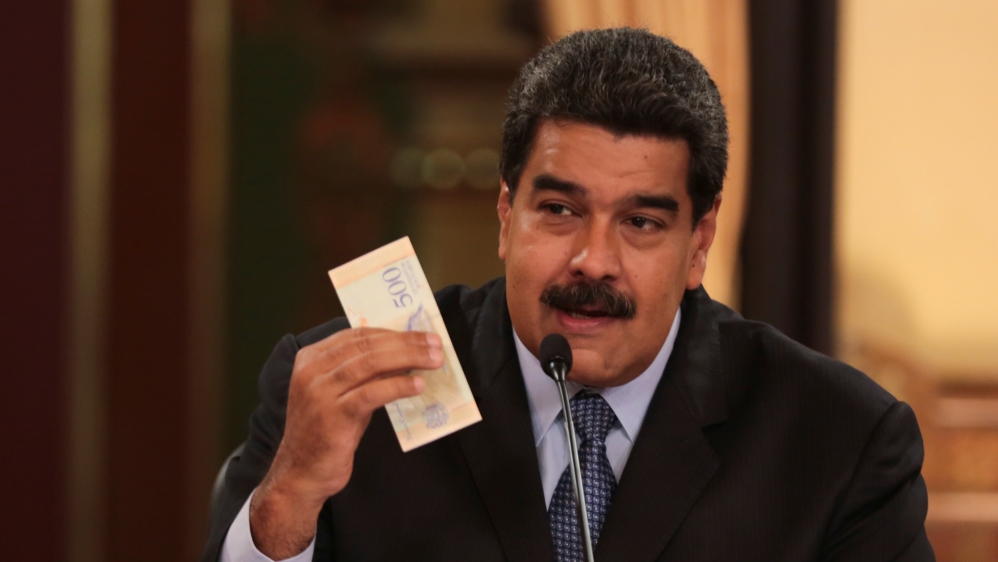 Venezuela's President Nicolas Maduro holds a bank note from the new Venezuelan currency Bolivar Soberano (Sovereign Bolivar) [Miraflores Palace handout/Reuters]