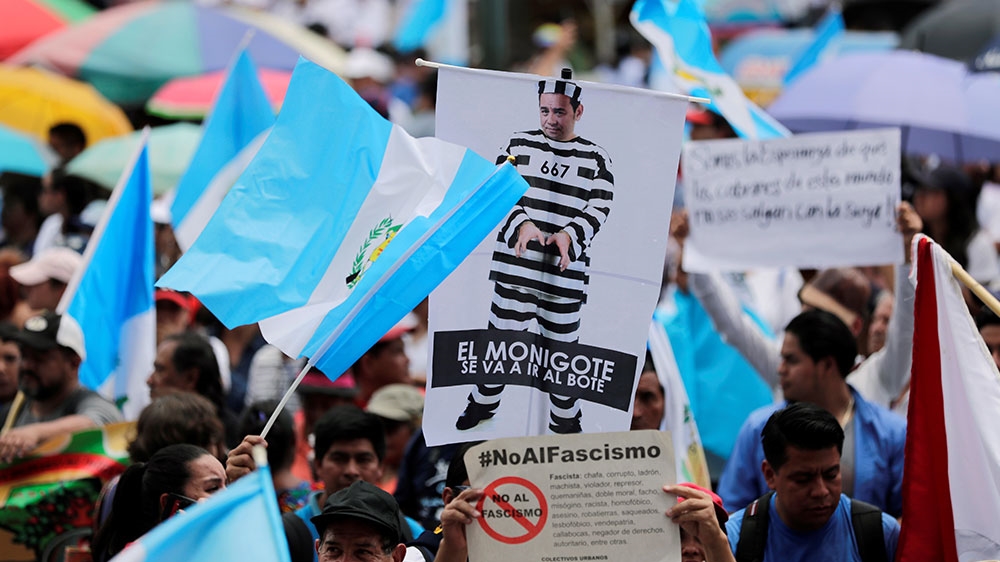 A demonstrator holds up a poster of Guatemala President Jimmy Morales as a prisoner, during a protest against Morales’s decision to not renew the mandate of CICIG