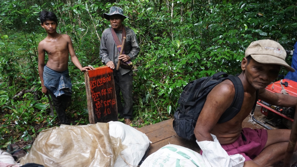 Patrol members stand by a post they erected marking the boundary of the Chom Penh forest. [Matt Blomberg/Al Jazeera]