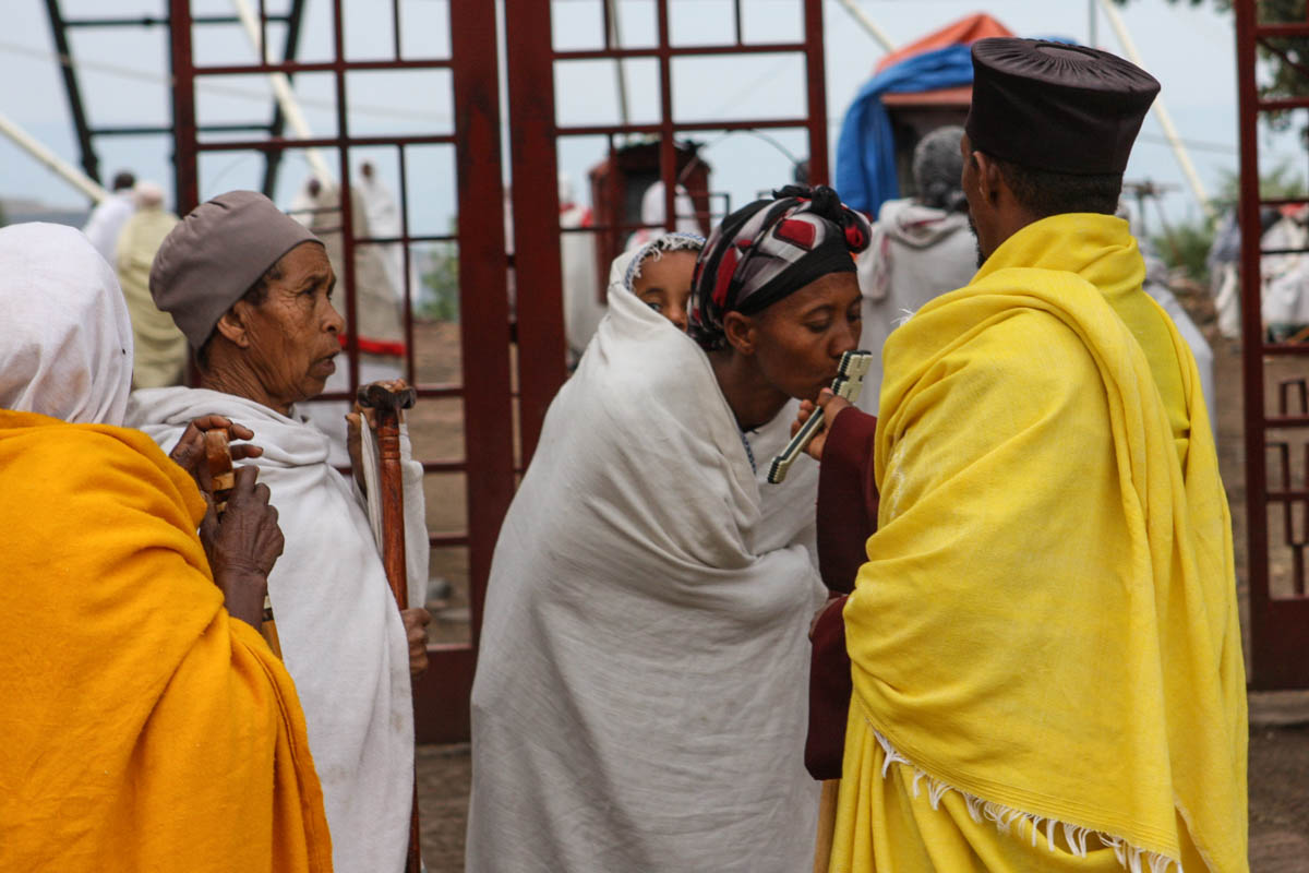 A church goer kisses a cross held out by a Lalibela priest. “We are willing to contribute to restoration, because we recognize our livelihoods depend on the churches,” says Deacon Mekonen Gebremeskal,