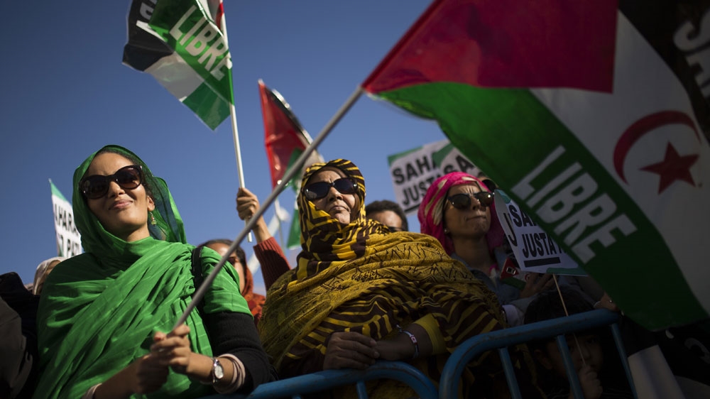 People hold Western Sahara flags as they listen to speeches during a protest