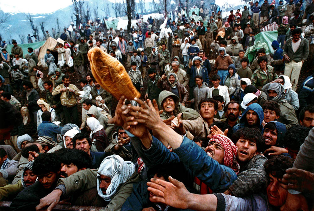 Frantic Kurdish refugees struggle for a loaf of bread during a humanitarian aid distribution at the Iraqi-Turkish border, April 5, 1991. REUTERS/Yannis Behrakis/File photo SEARCH "YANNIS BEHRAKIS" FO