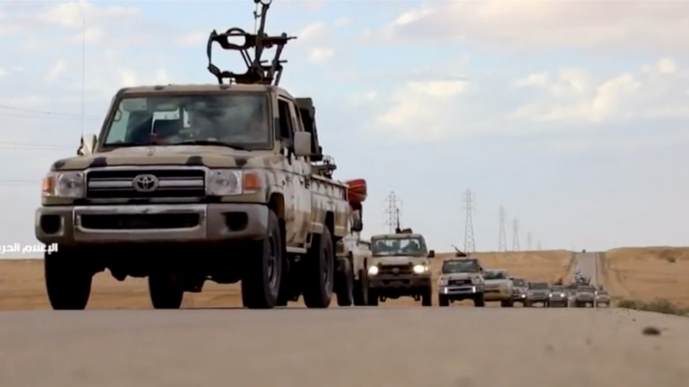 Pickup trucks with mounted weapons drive on a road in Libya
