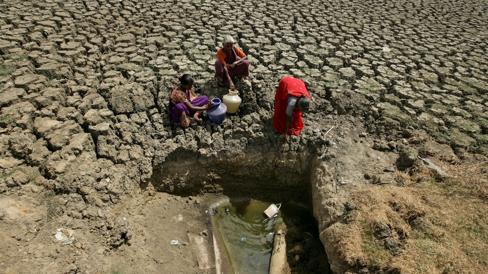 Women fetch water from an opening made by residents at a dried-up lake near Chennai, India