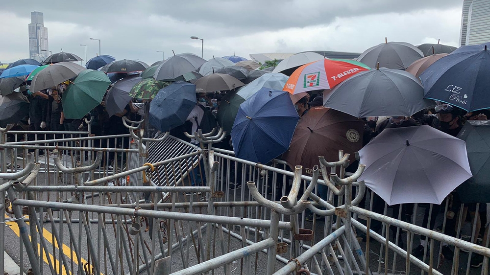 Protesters outside Hong Kong’s legislature attempt to protect themselves with umbrellas in anticipation of a pepper spray attack from police