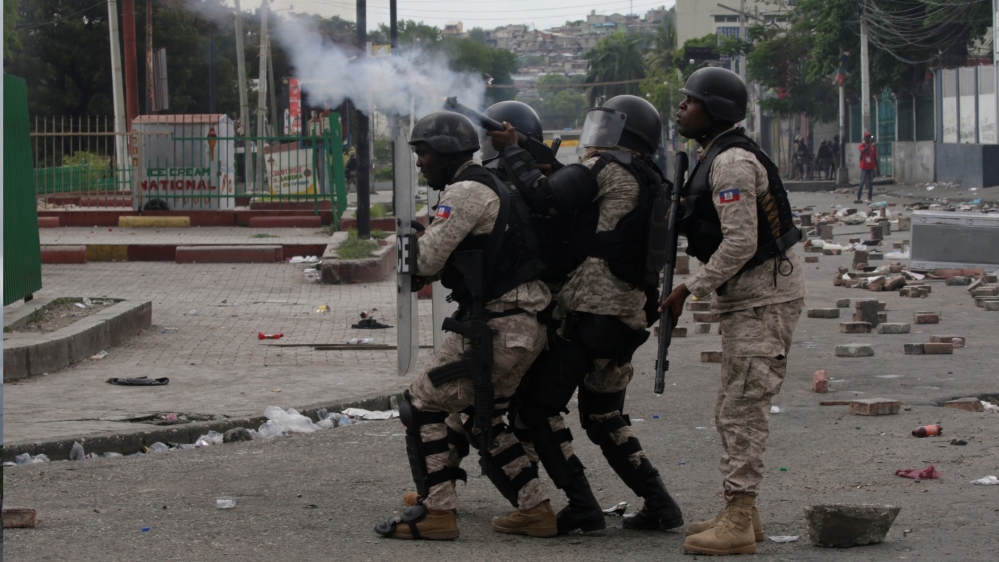 Haitian National Police (PNH) officers fire tear gas towards protesters during the protest